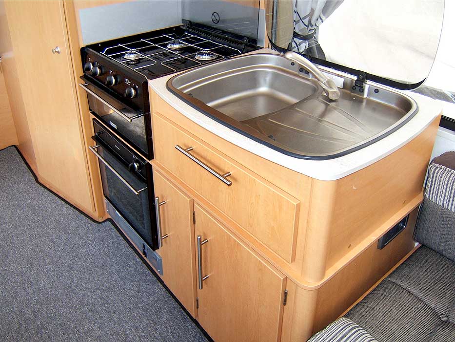 The 'kitchen' area, with hob, oven, stainless steel sink and storage.